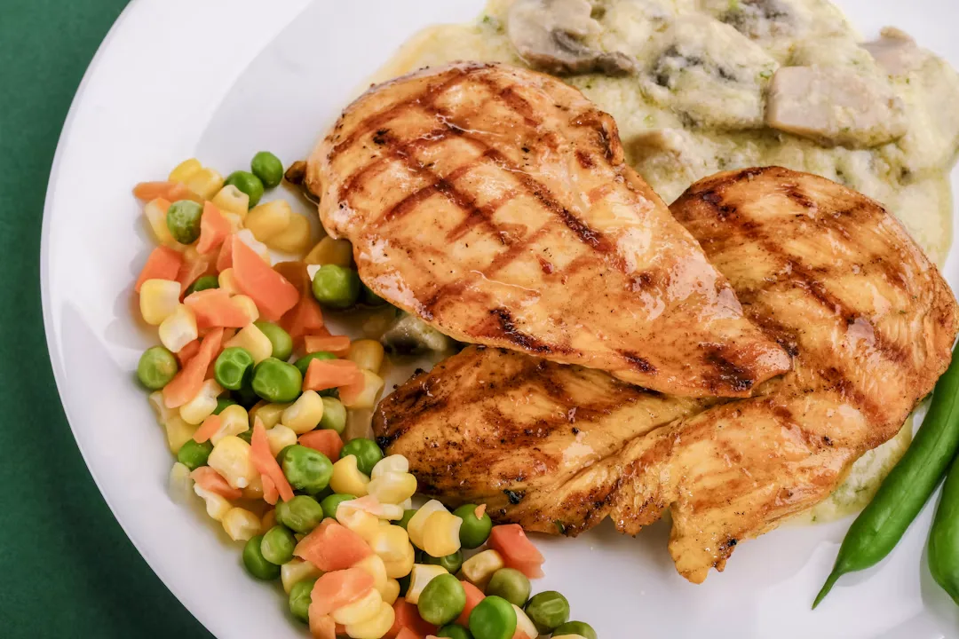 Golden roasted sheet pan chicken thighs with red peppers onions and herbs on parchment paper