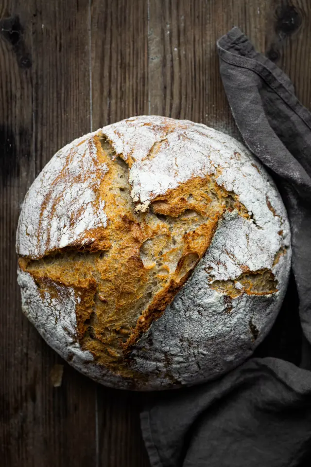 Artisan loaf of freshly baked scored sourdough bread on a wooden board