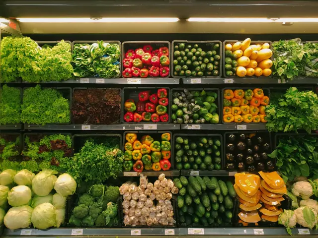 Modern grocery store produce aisle with organized fresh fruits vegetables and shopping cart