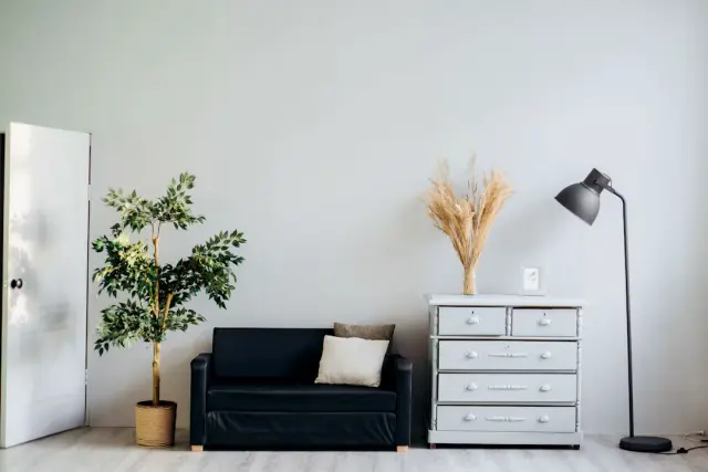 Bright sunlit bedroom with light neutral walls sheer curtains and glowing ambient floor lamp