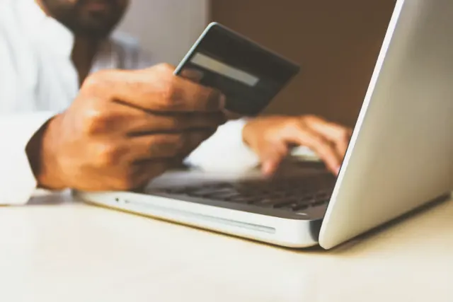 Person holding smartphone with shopping app open pausing before checkout on clean desk