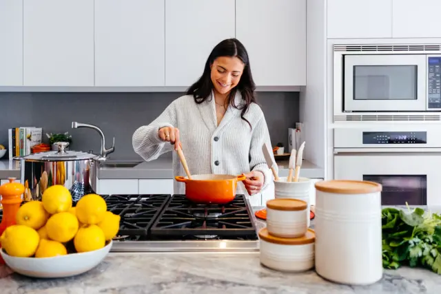 Open wooden kitchen shelving styled with ceramic plates glassware wooden cutting boards and plant