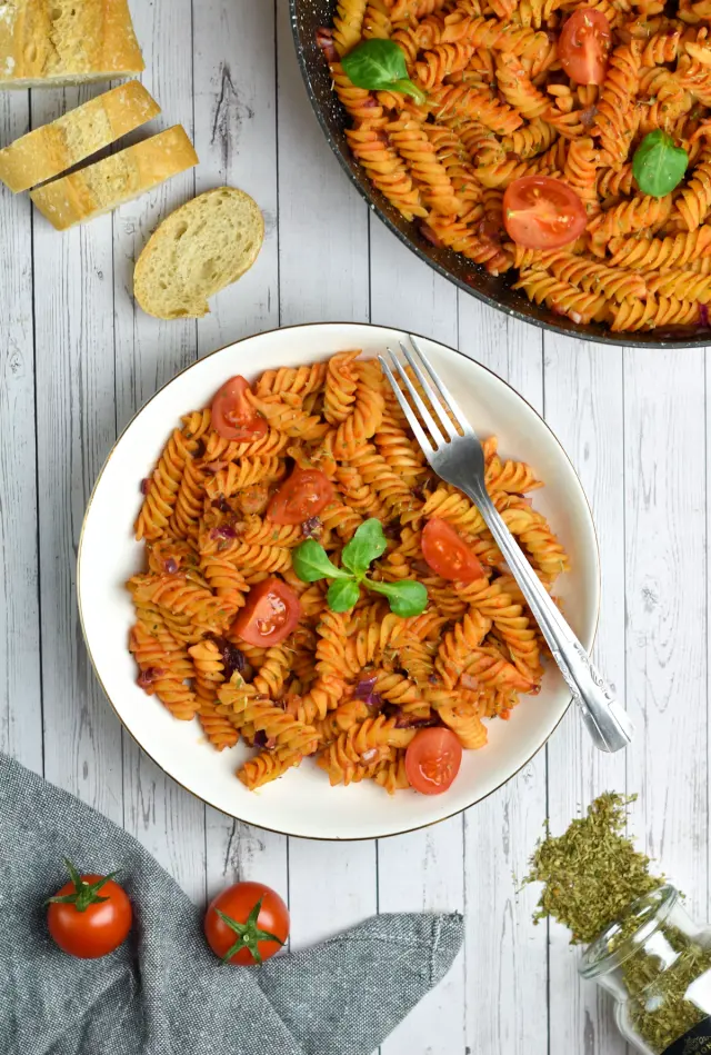 Bowl of rich creamy garlic herb pasta garnished with fresh parmesan and parsley
