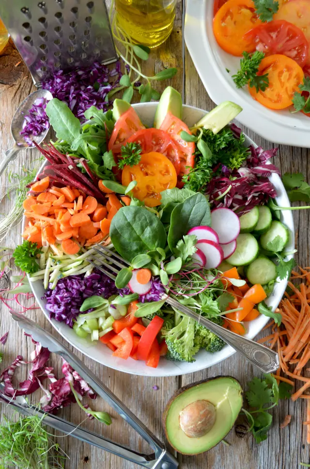 Fresh avocado salad bowl with chickpeas greens and lemon dressing on a desk